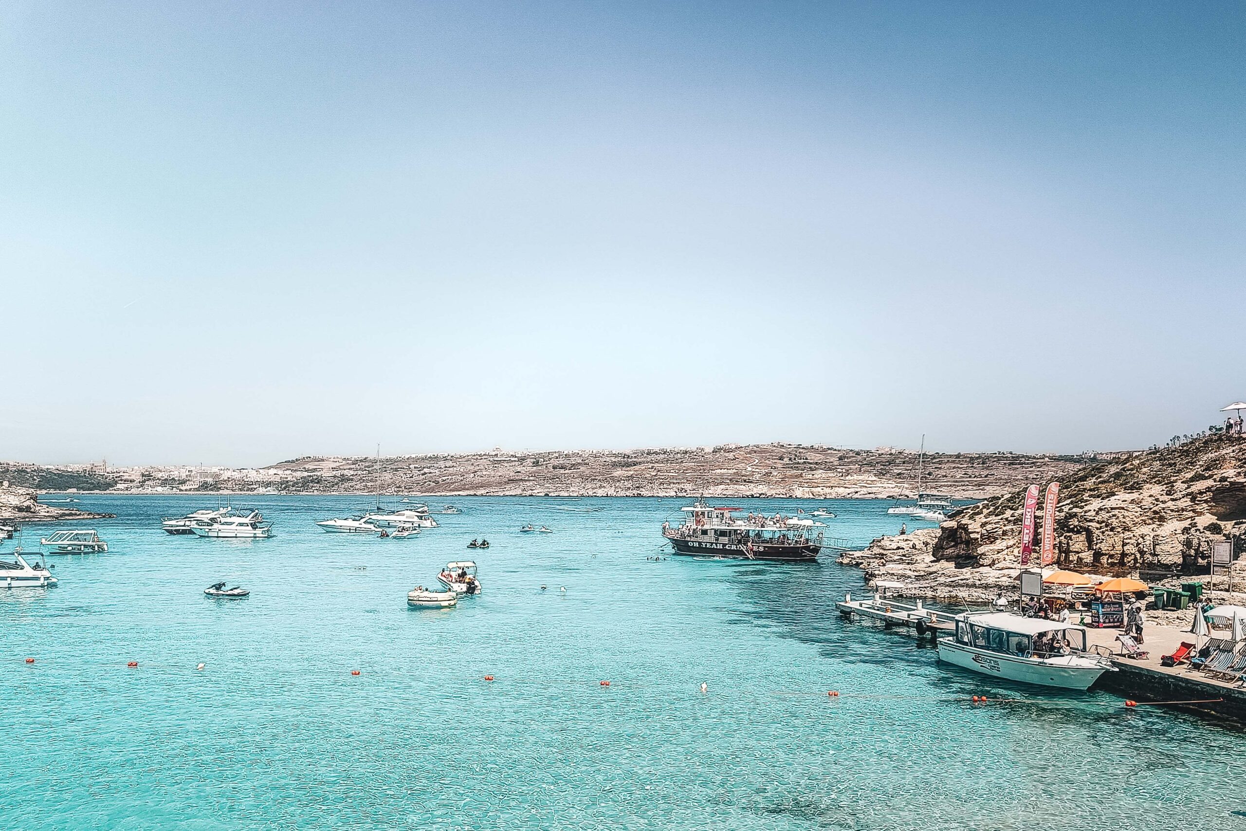 Boats and swimmers at the Blue Lagoon in Comino island, Malta on a sunny day