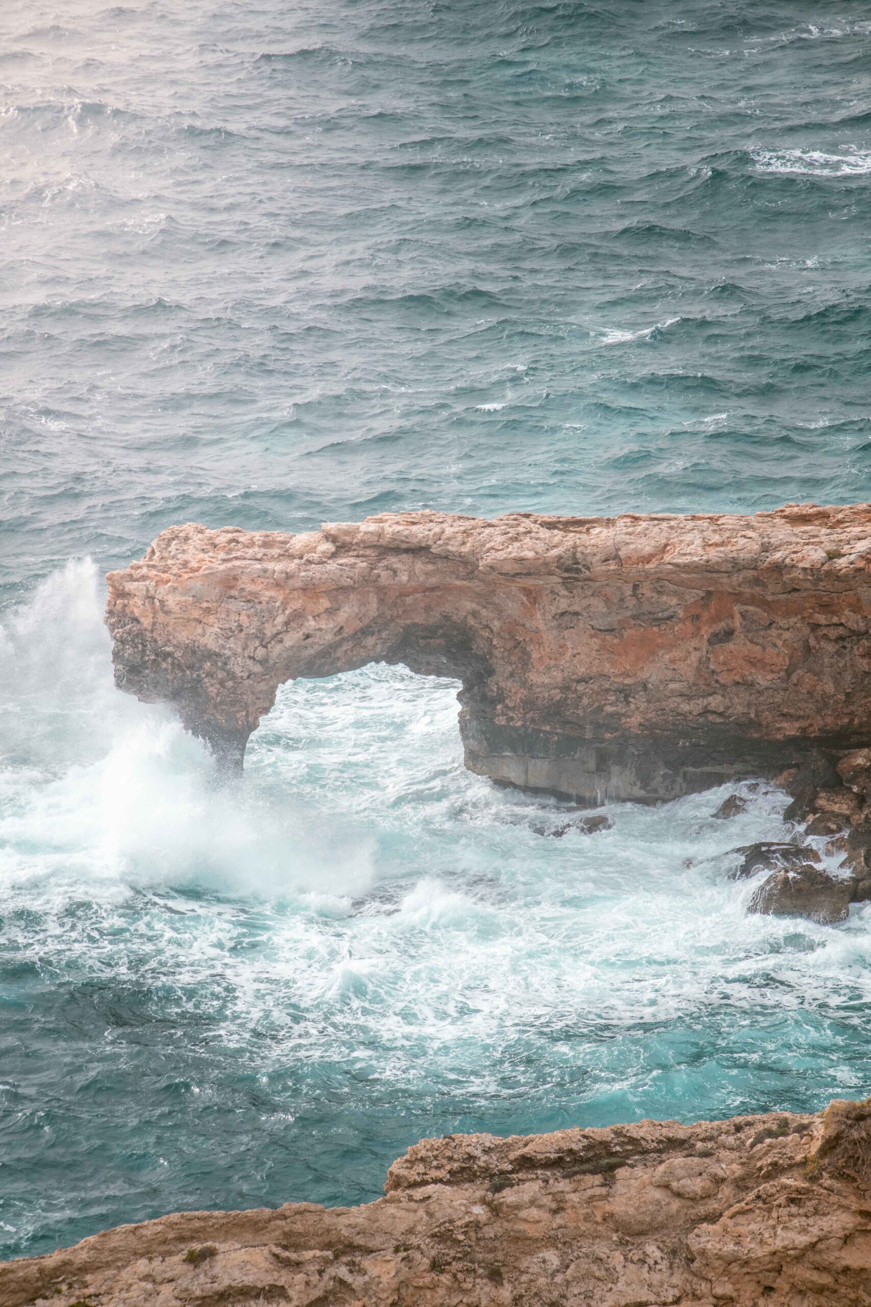 Crashing waves against the Għar Ħanex window near Ħaġar Qim and Mnajdra archaeological park in Il-Qrendi, Malta