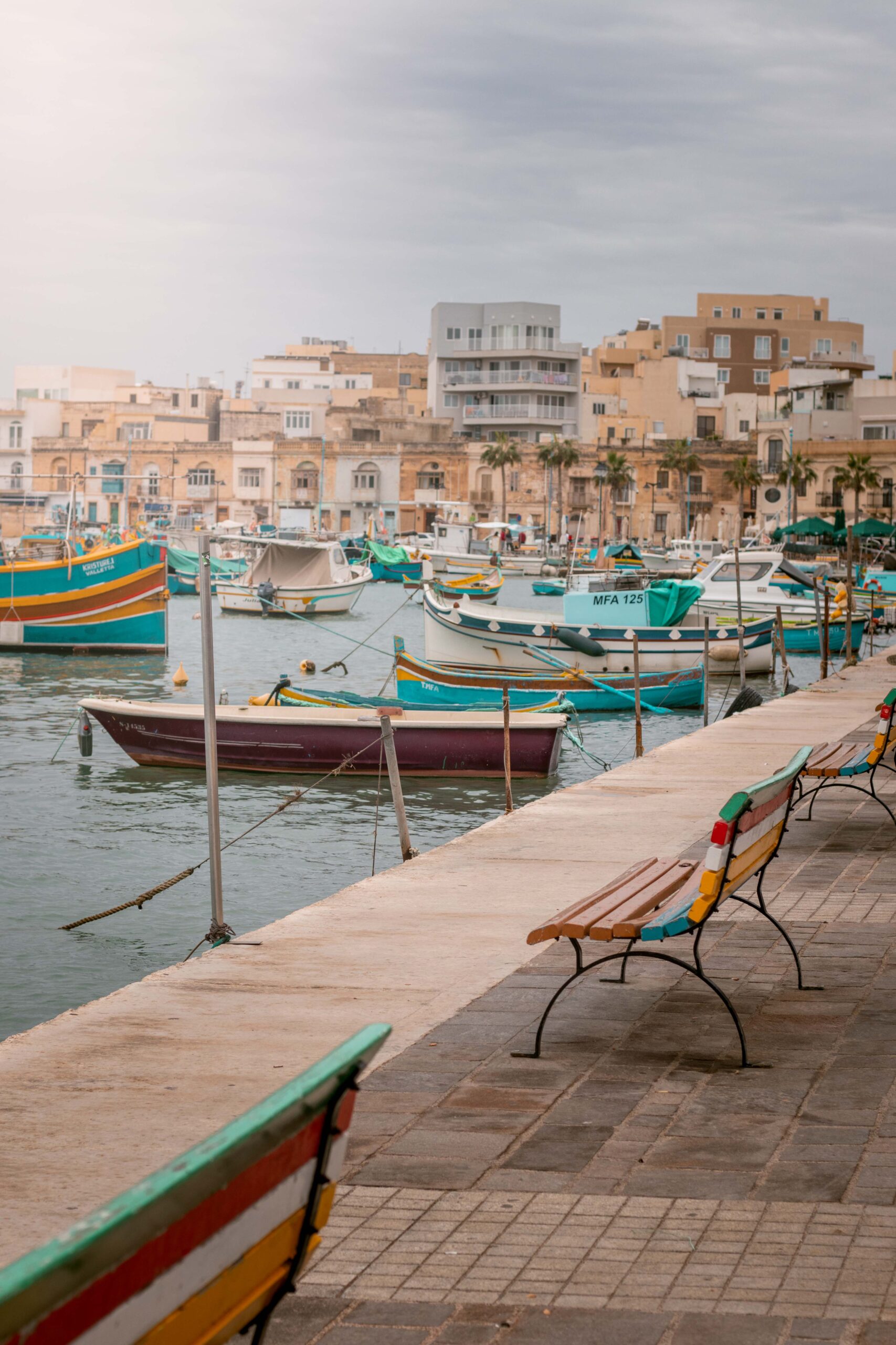 Colourful benches and traditional luzzu boats in Marsaxlokk Harbour, Malta