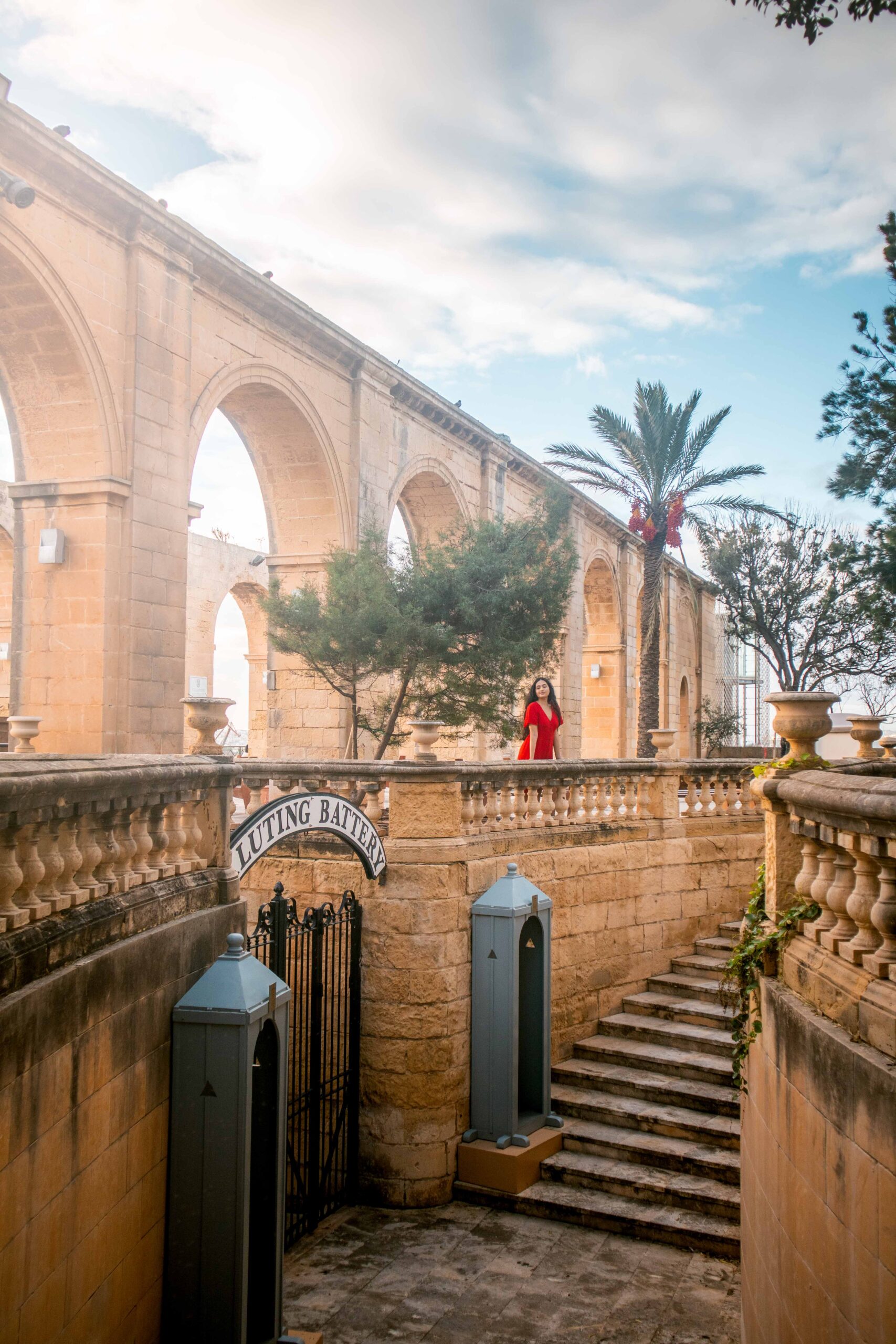 Woman wearing a red dress near the stairs of the Saluting Battery in the Upper Barrakka Gardens of Valletta, Malta