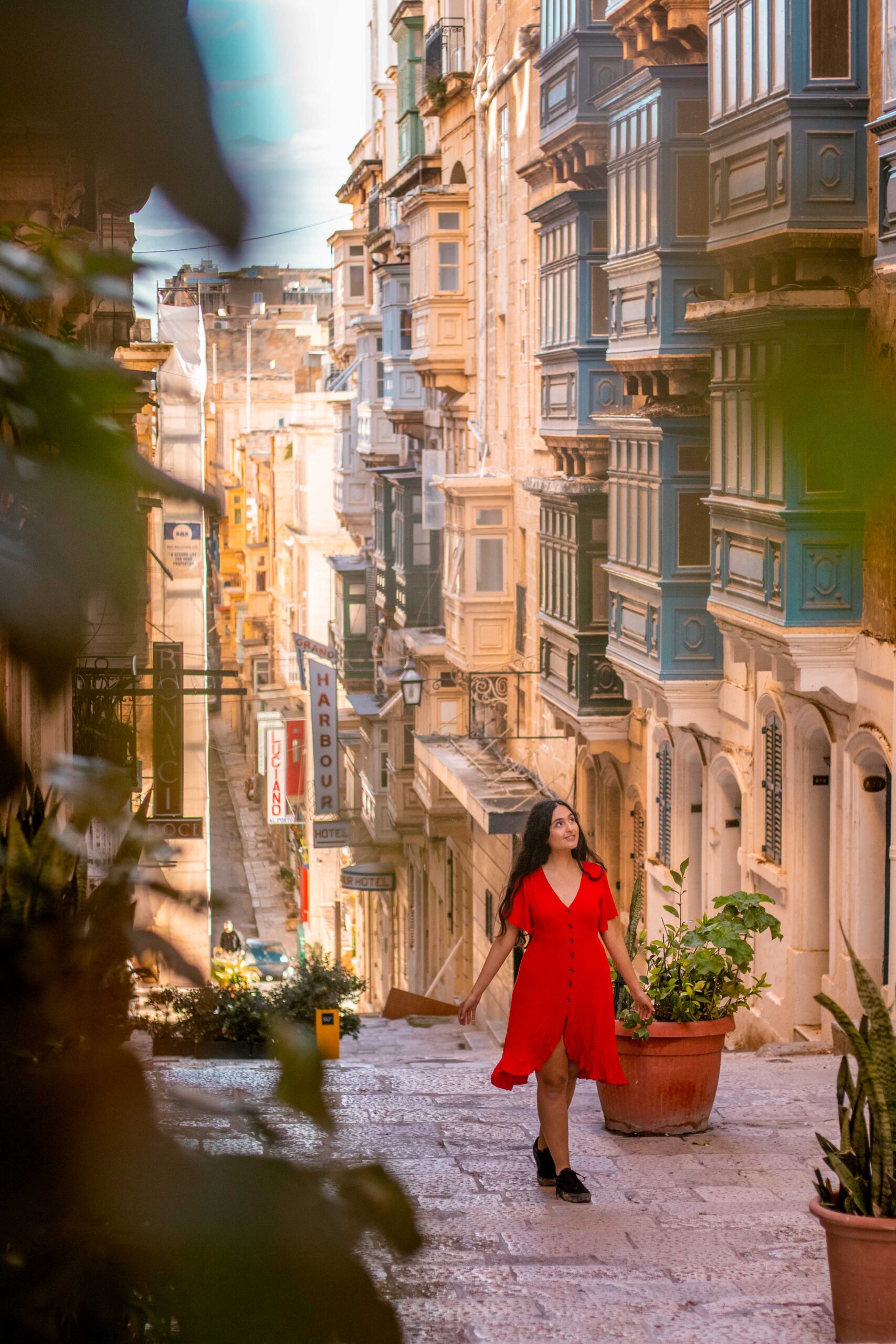 Woman wearing a red dress in the street of Triq Sant' Orsla in Valletta, Malta