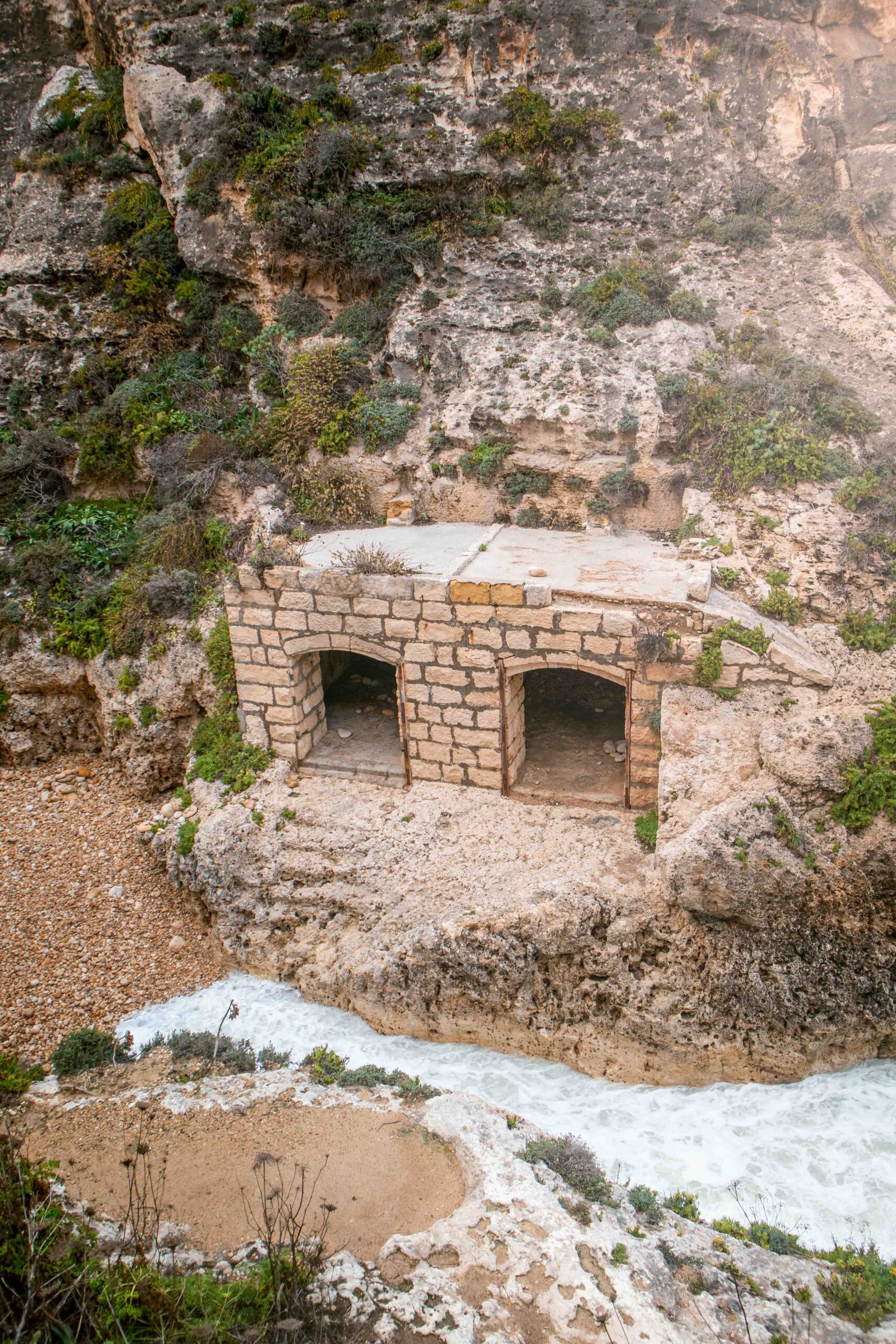 Small pebble beach and stone shelter of Wied Il-Għasri gorge on Gozo island, Malta