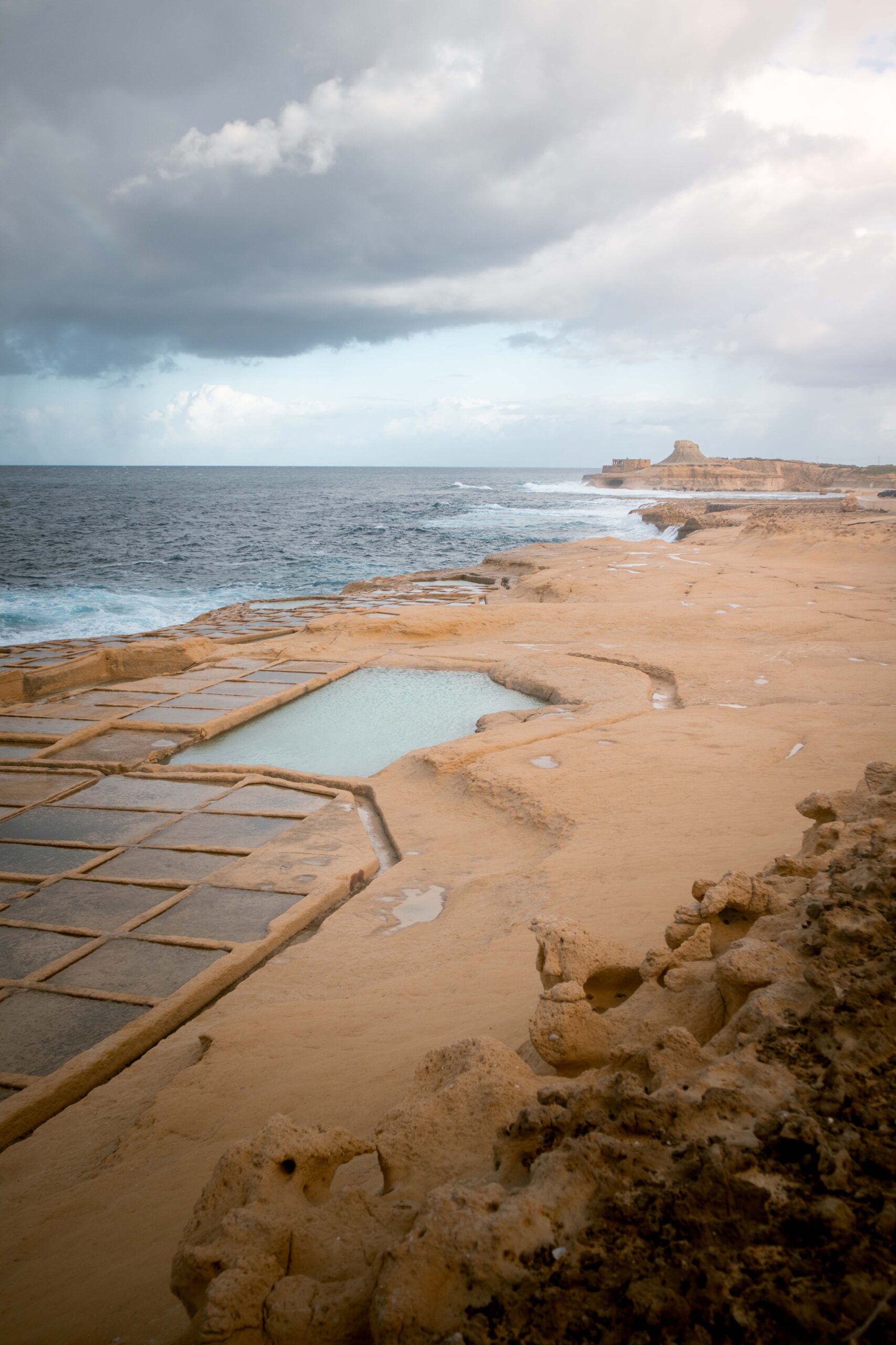 Agitated sea at Xwejni Salt Pans in Gozo island, Malta with a distant view of Xwejni Rock and Qolla l-Bajda