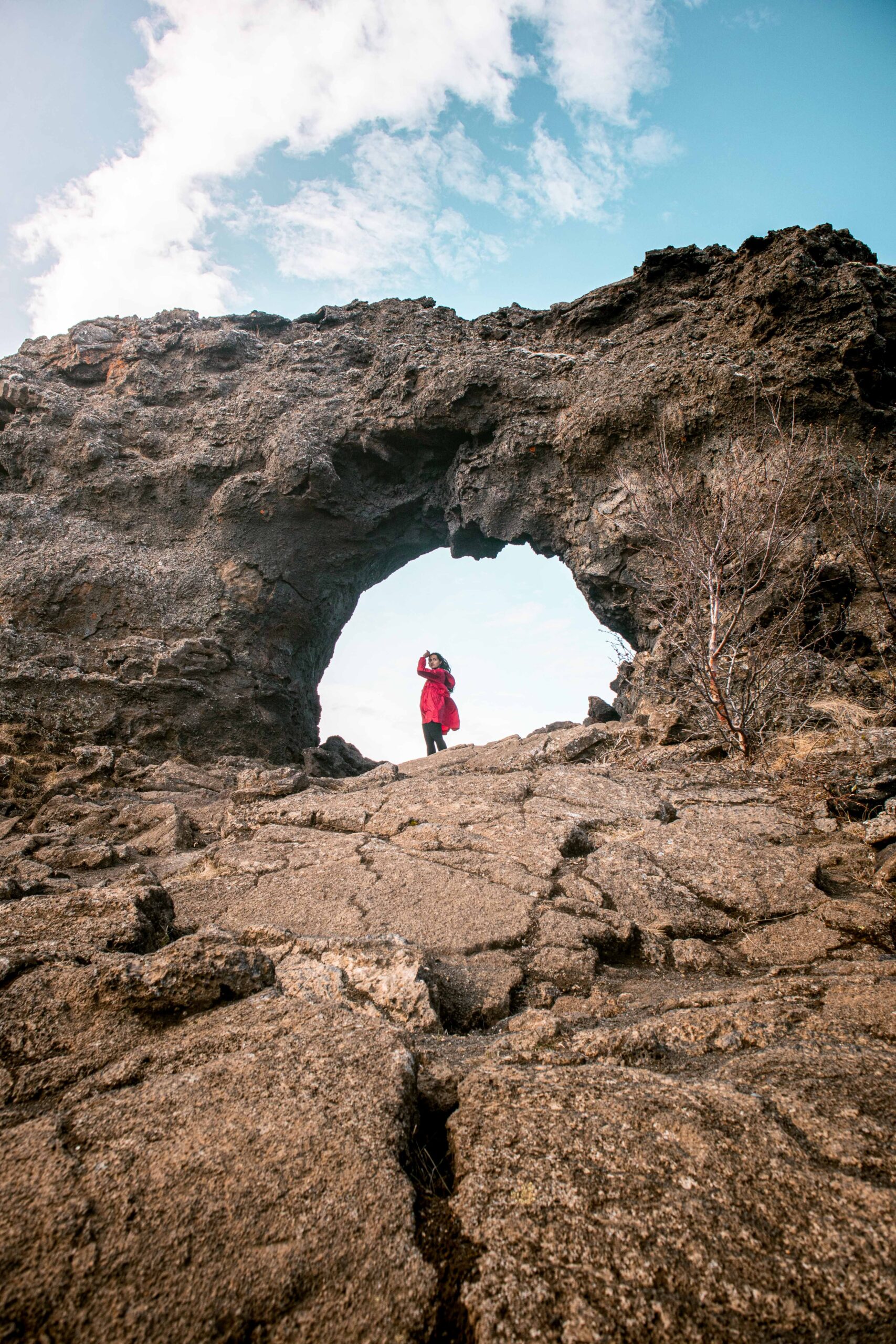 Woman standing at Gatklettur Arch in Dimmuborgir lava fields at Mývatn Lake Area, North Iceland