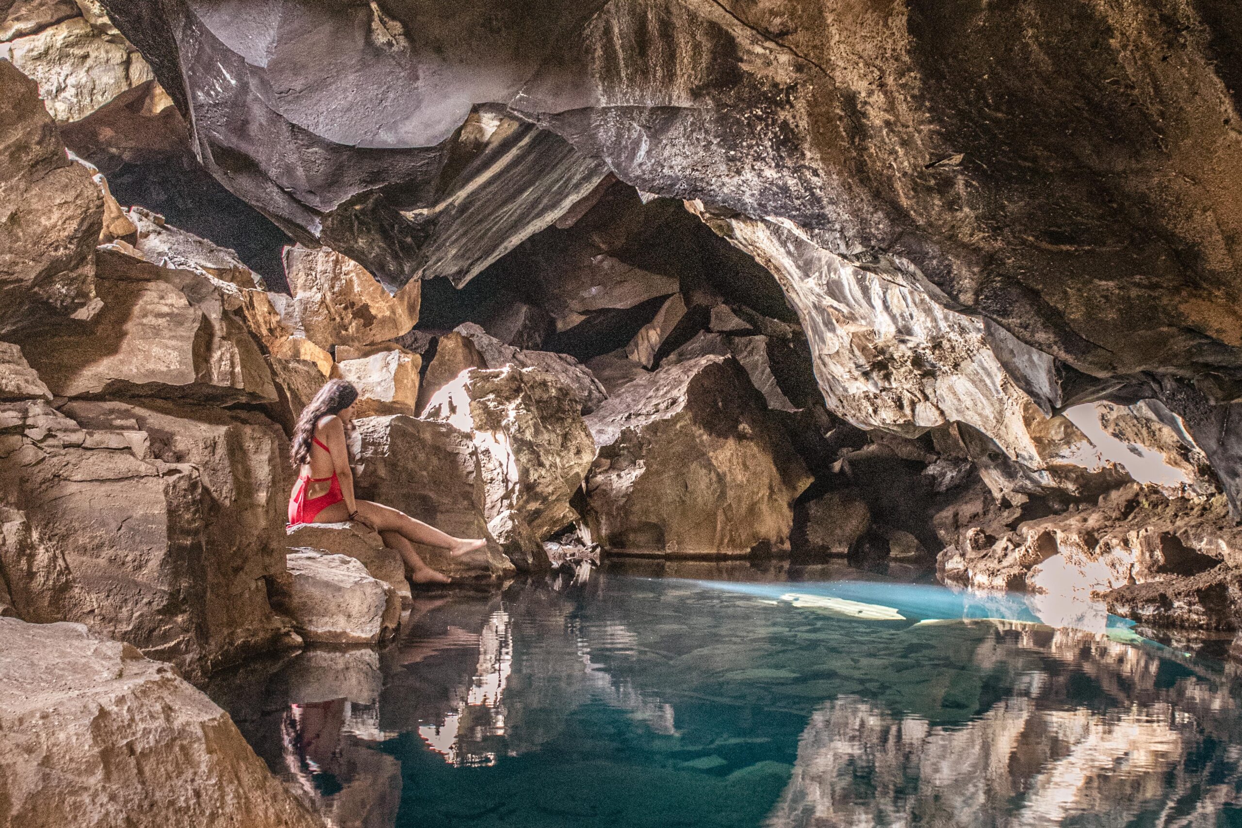 Woman posing at the edge of the hot spring in Grjotagja cave in Lake Mývatn area, North Iceland