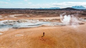 Drone view of a woman standing in Hverir (Hverarönd) geothermal area near Lake Mývatn, North Iceland