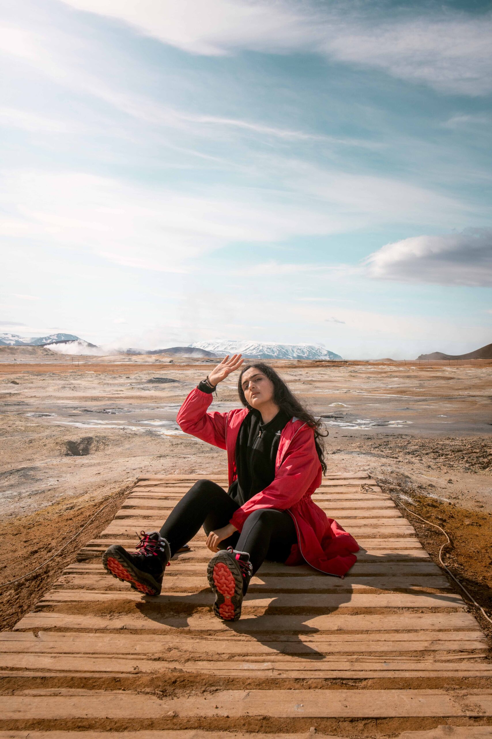 Woman sitting on a boardwalk in Hverir (Hverarönd) geothermal area near Lake Mývatn, North Iceland