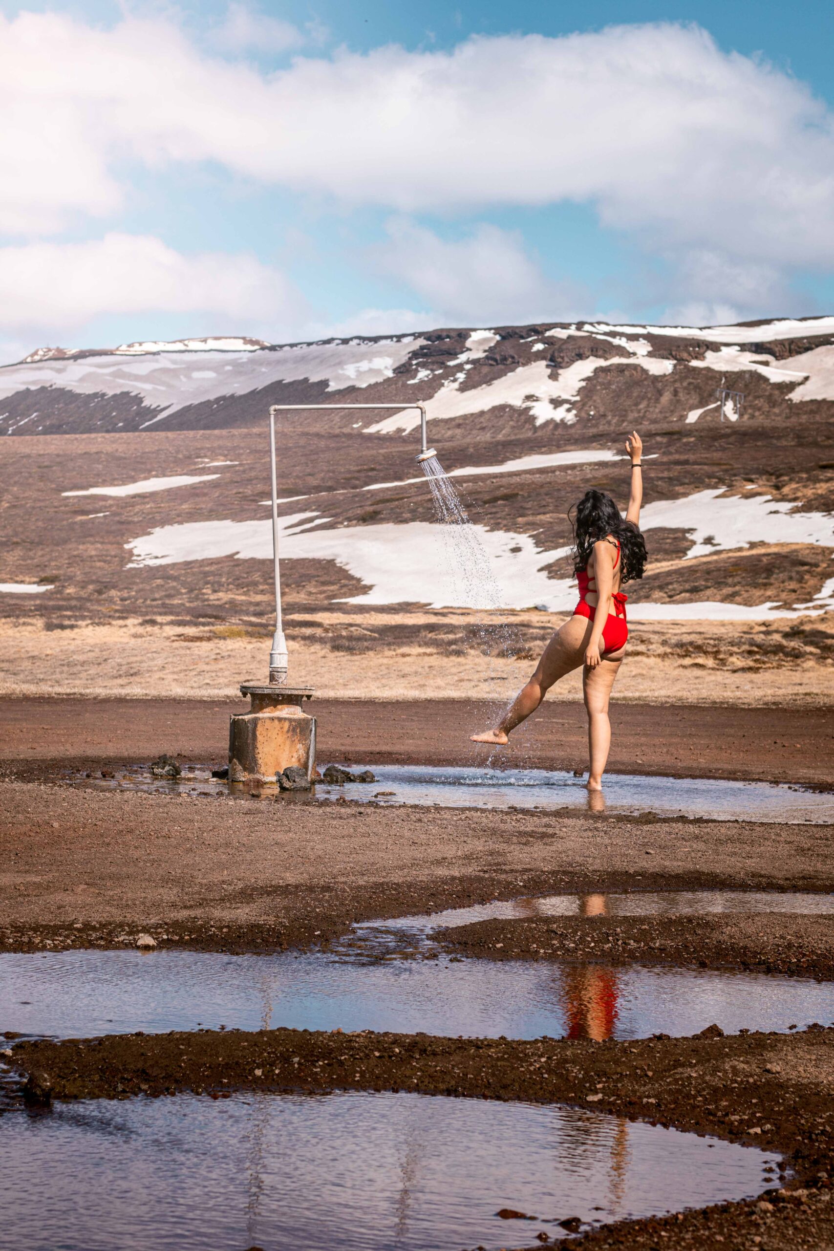 Woman posing under infinite geothermal hot shower (perpetual shower) in Krafla volcanic area near Lake Mývatn, North Iceland