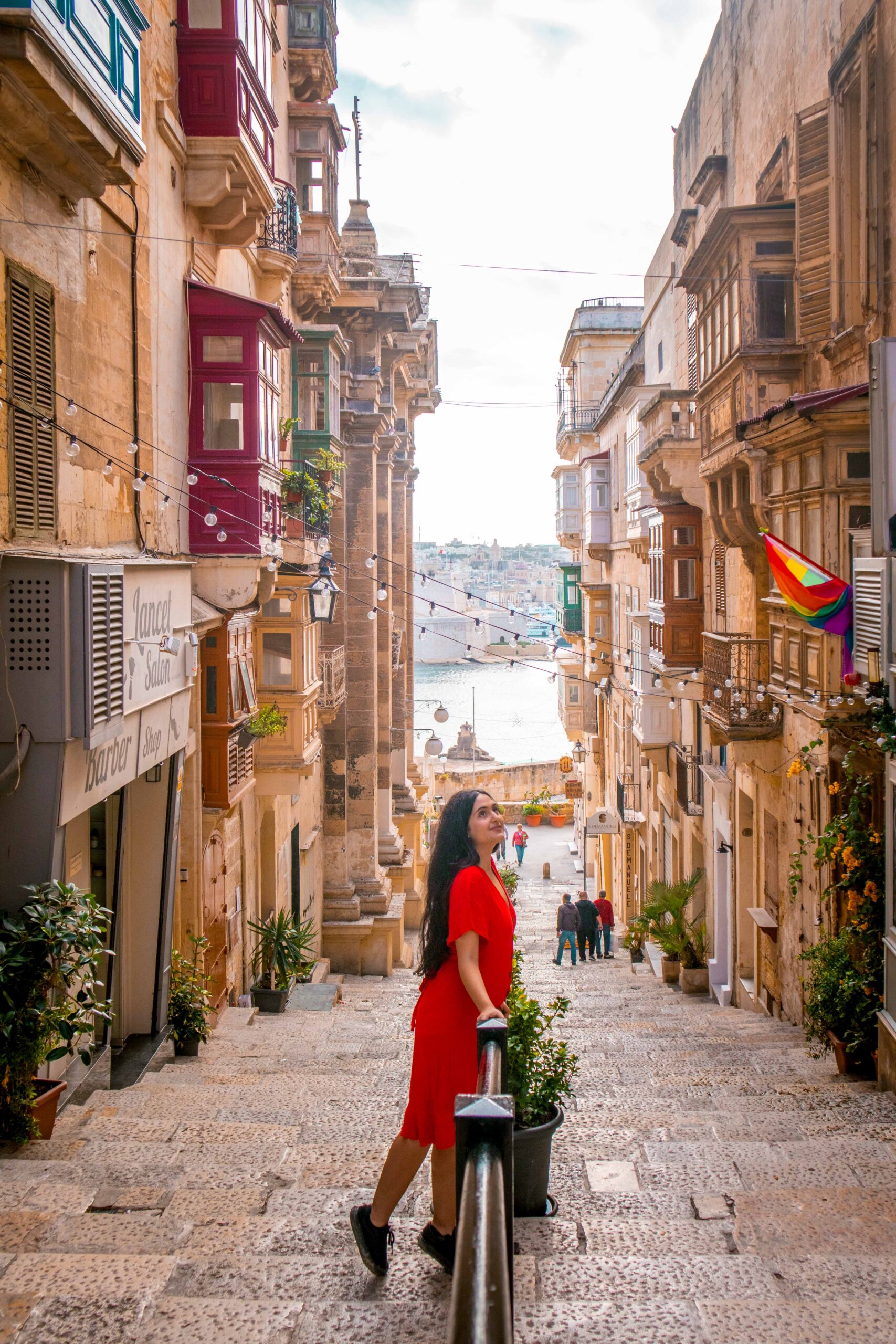 Woman wearing a red dress in the street of Triq San Gwann in Valletta, Malta
