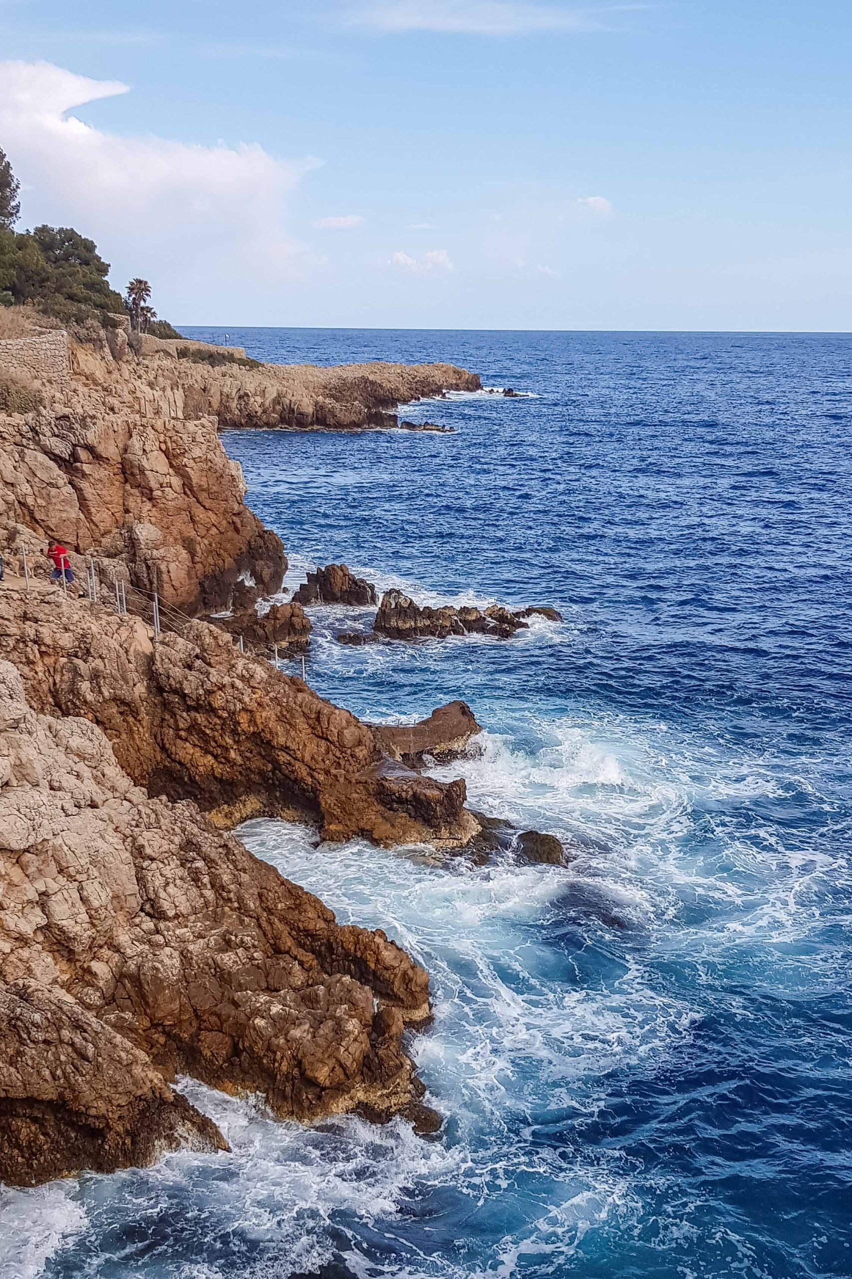 Rock cliffs and view of the Mediterranean Sea along the Sentier du Littoral hiking trail during a sunny day in Antibes, France