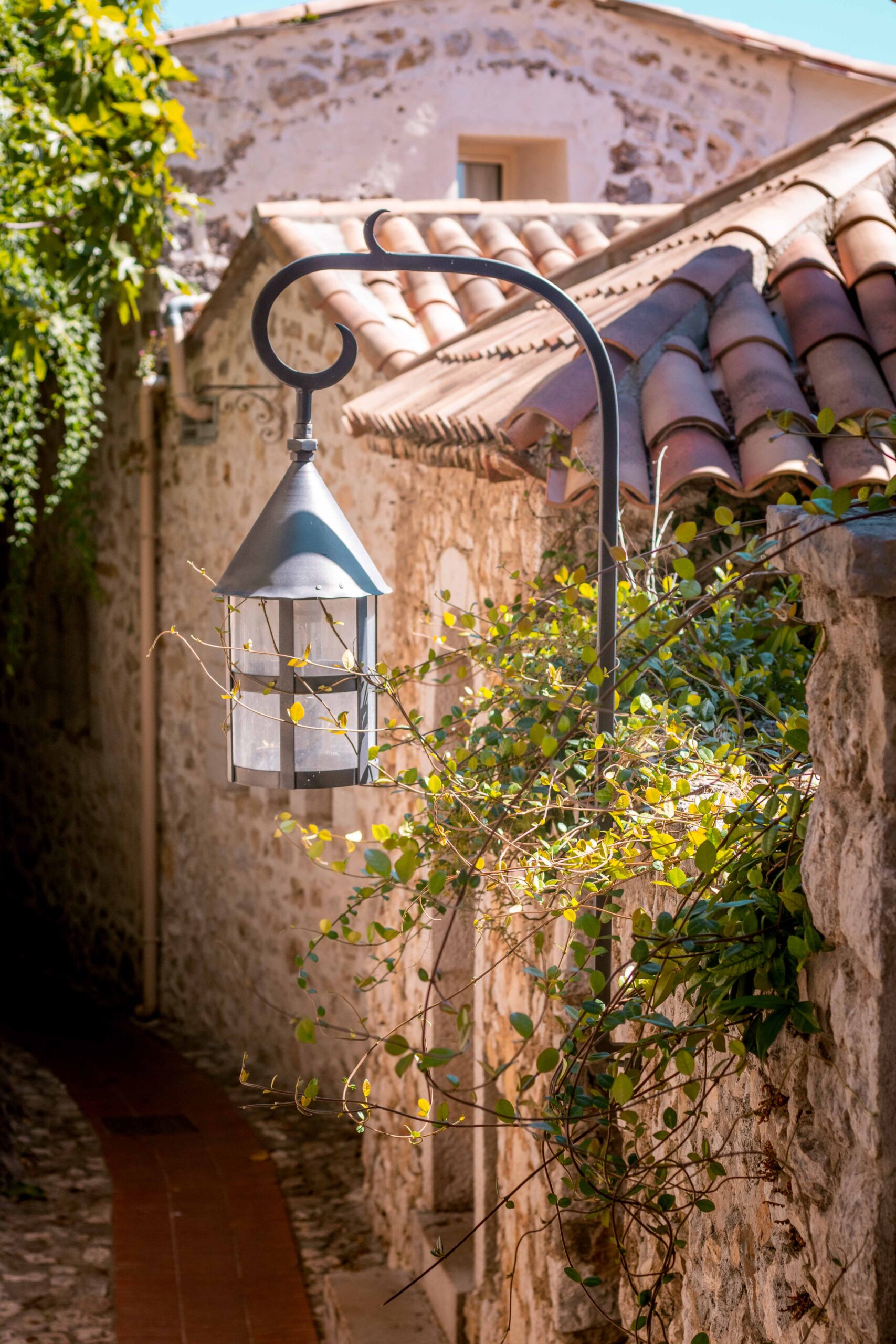 Detail of a lantern and plants in a small cobblestone street in Eze Village, France