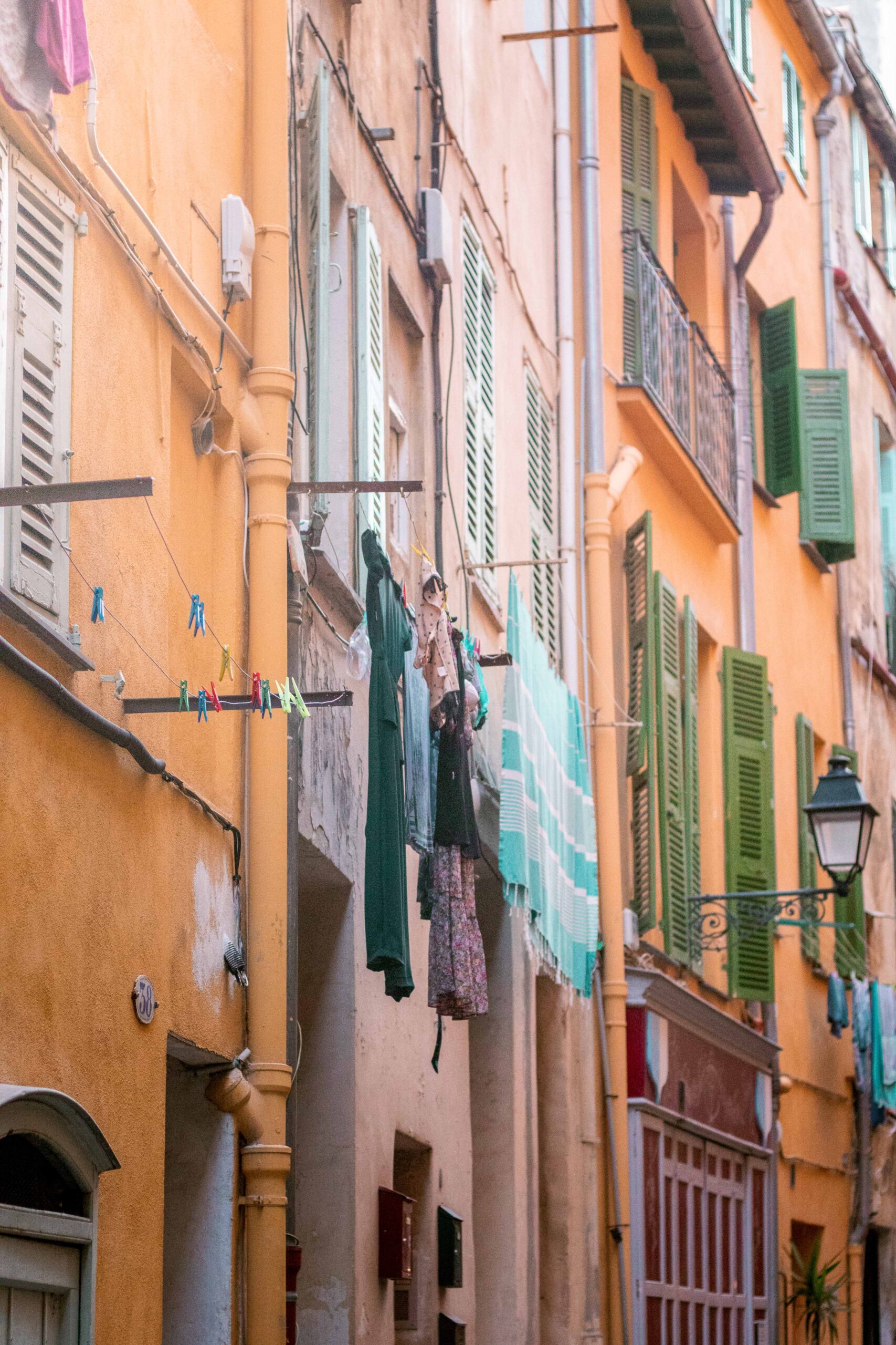 Hanging clothes drying on the balcony of colourful buildings with yellow and orange facades in the Old Town of Menton, France
