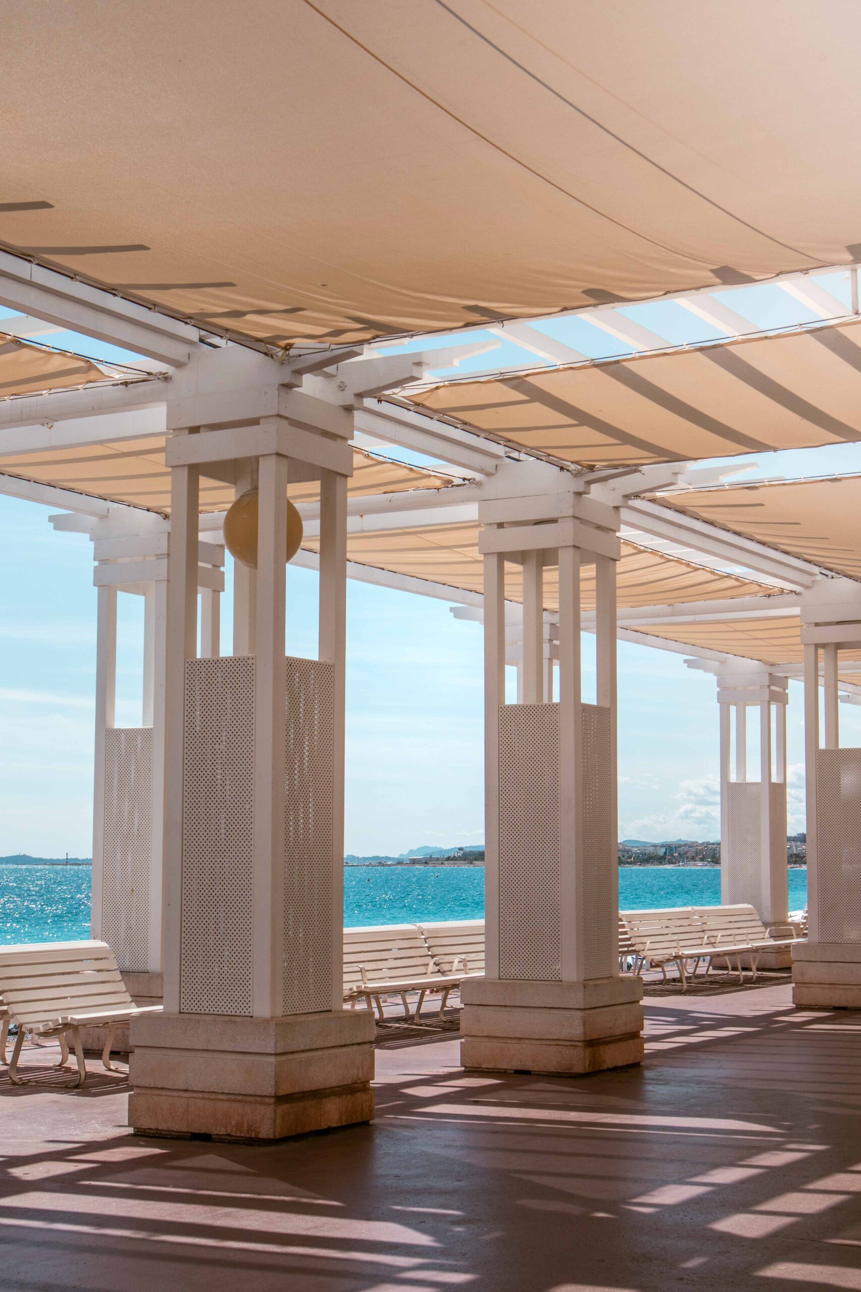 White pergola and benches next to the sea on the Promenade des Anglais in Nice, France