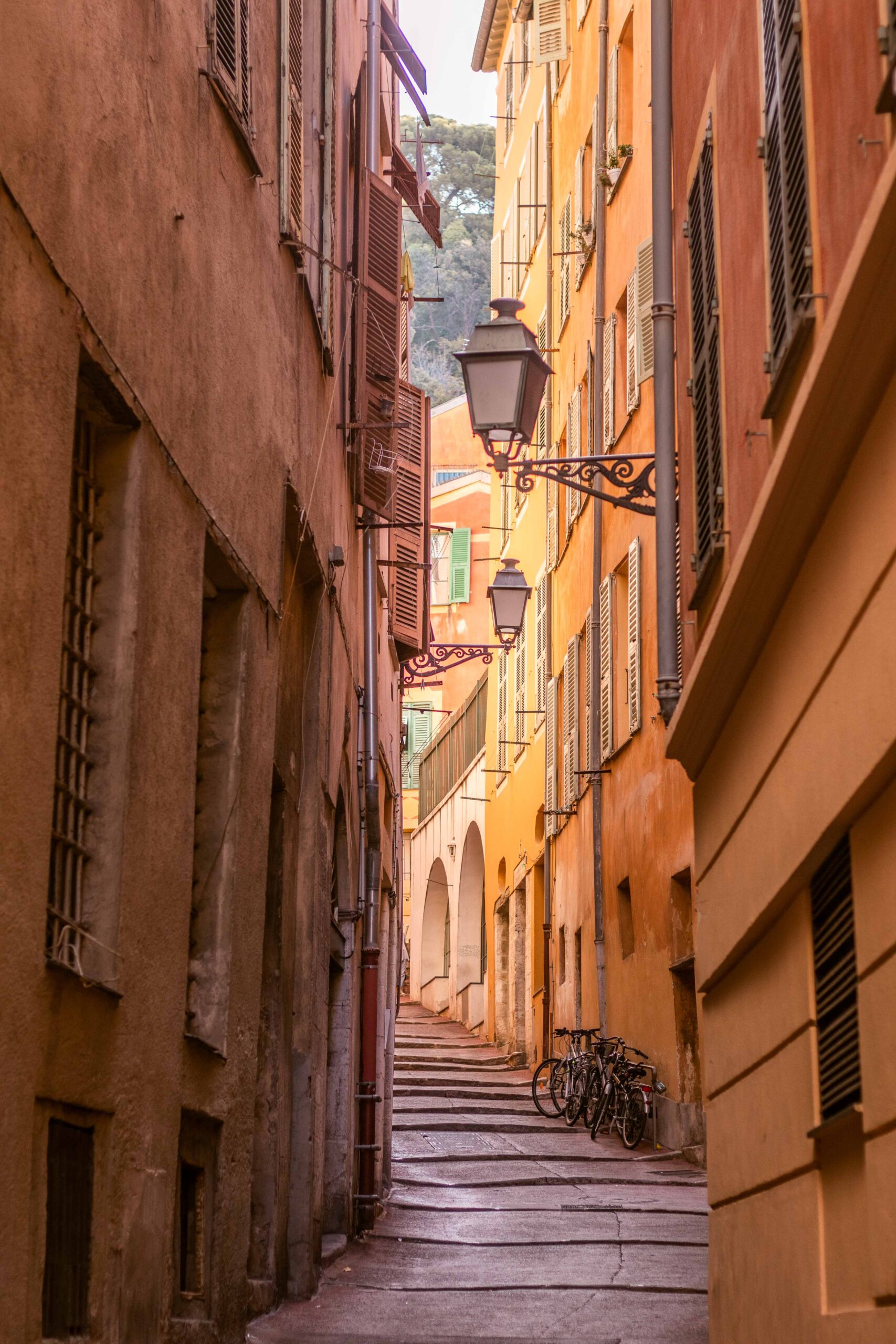 Narrow colourful and empty street in the Old Town of Nice (Vieux-Nice) with orange and yellow buildings in Nice, France