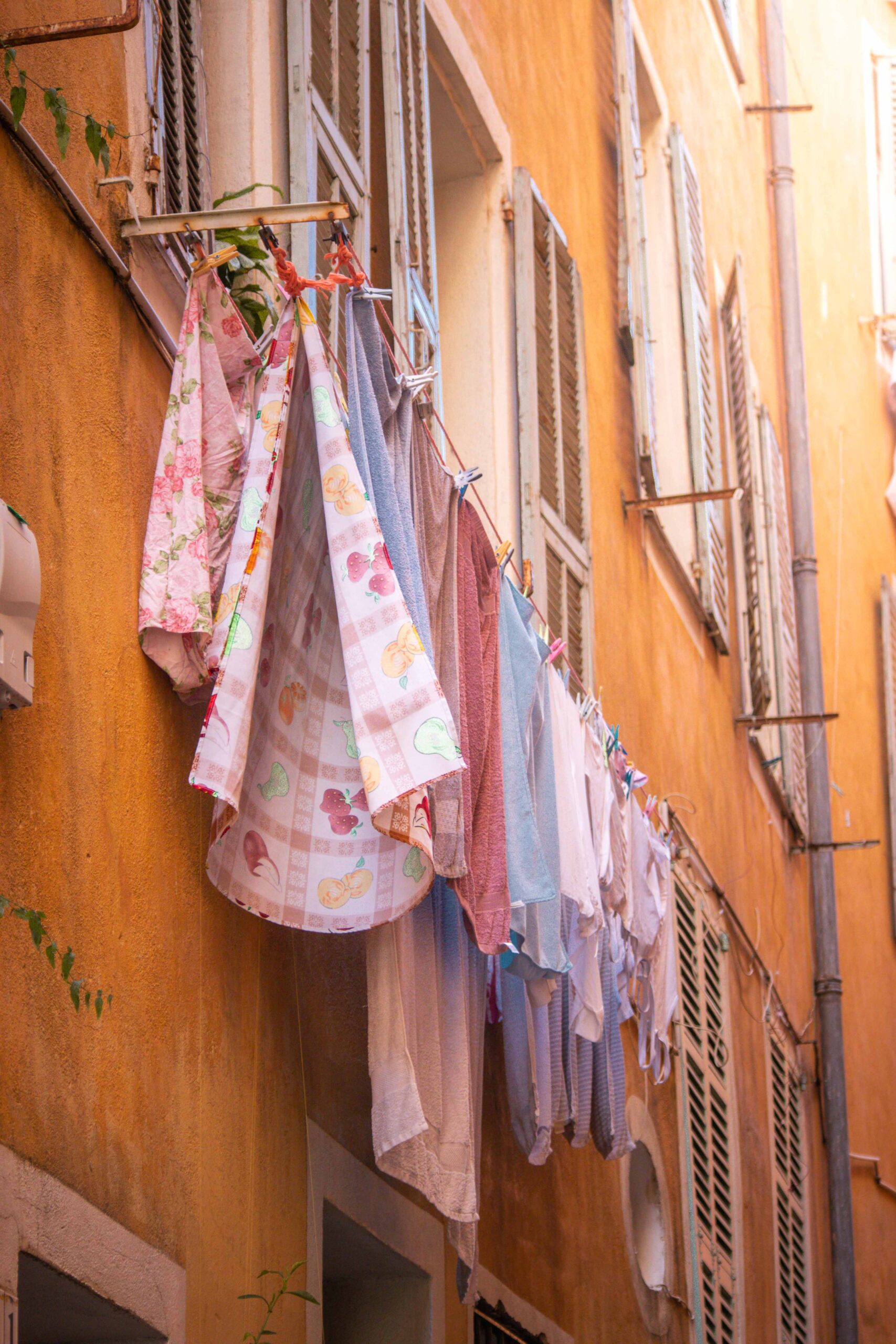 Hanging clothes drying on the balcony of colourful buildings with yellow and orange facades in the Old Town of Nice (Vieux-Nice) in Nice, France