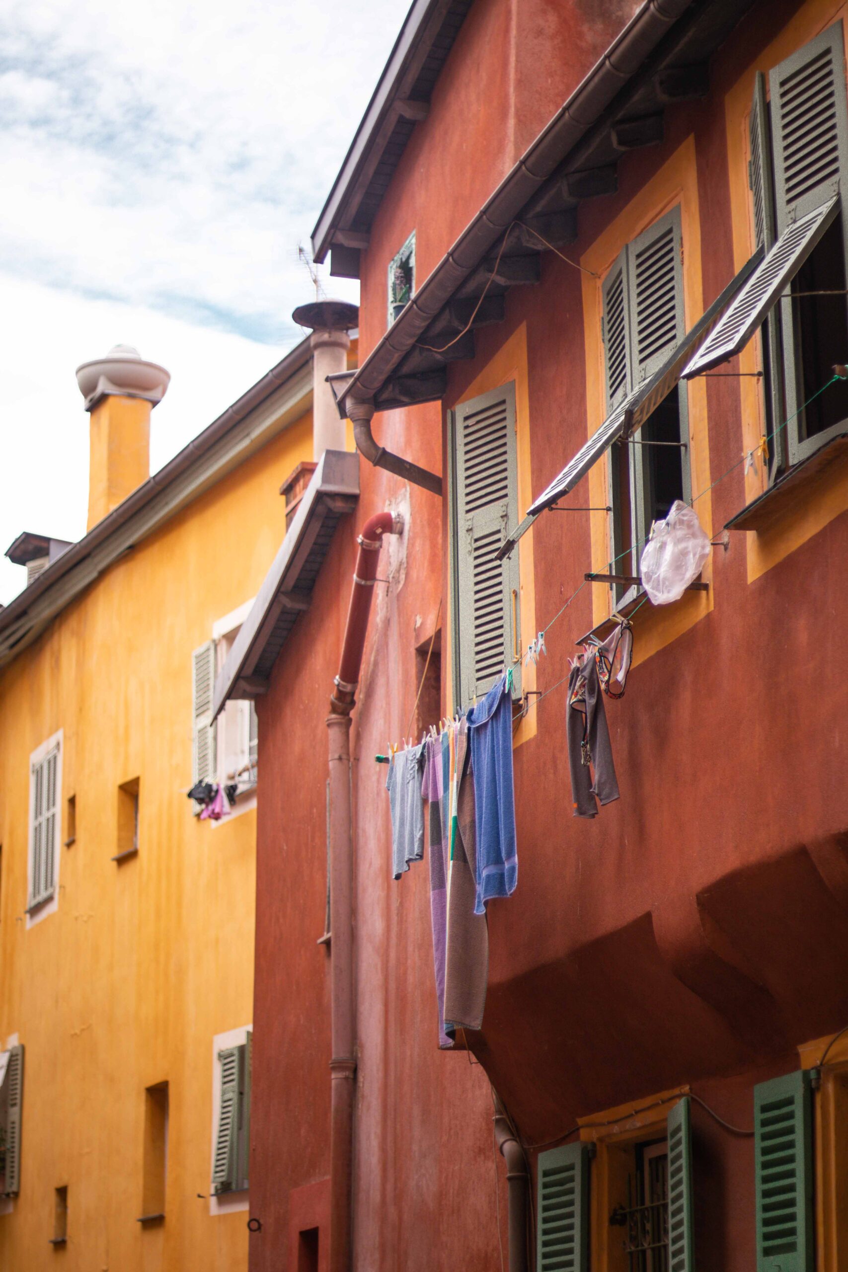 Hanging clothes drying on the balcony of colourful buildings with red and orange facades in the Old Town of Nice (Vieux-Nice) in Nice, France