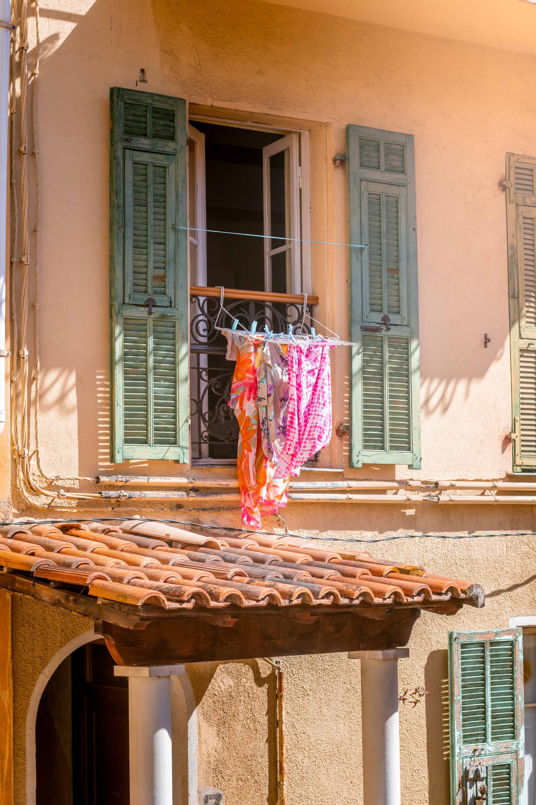 Hanging clothes drying on the balcony of colourful buildings facades on a sunny day in the Old Town of Villefranche-sur-Mer, France