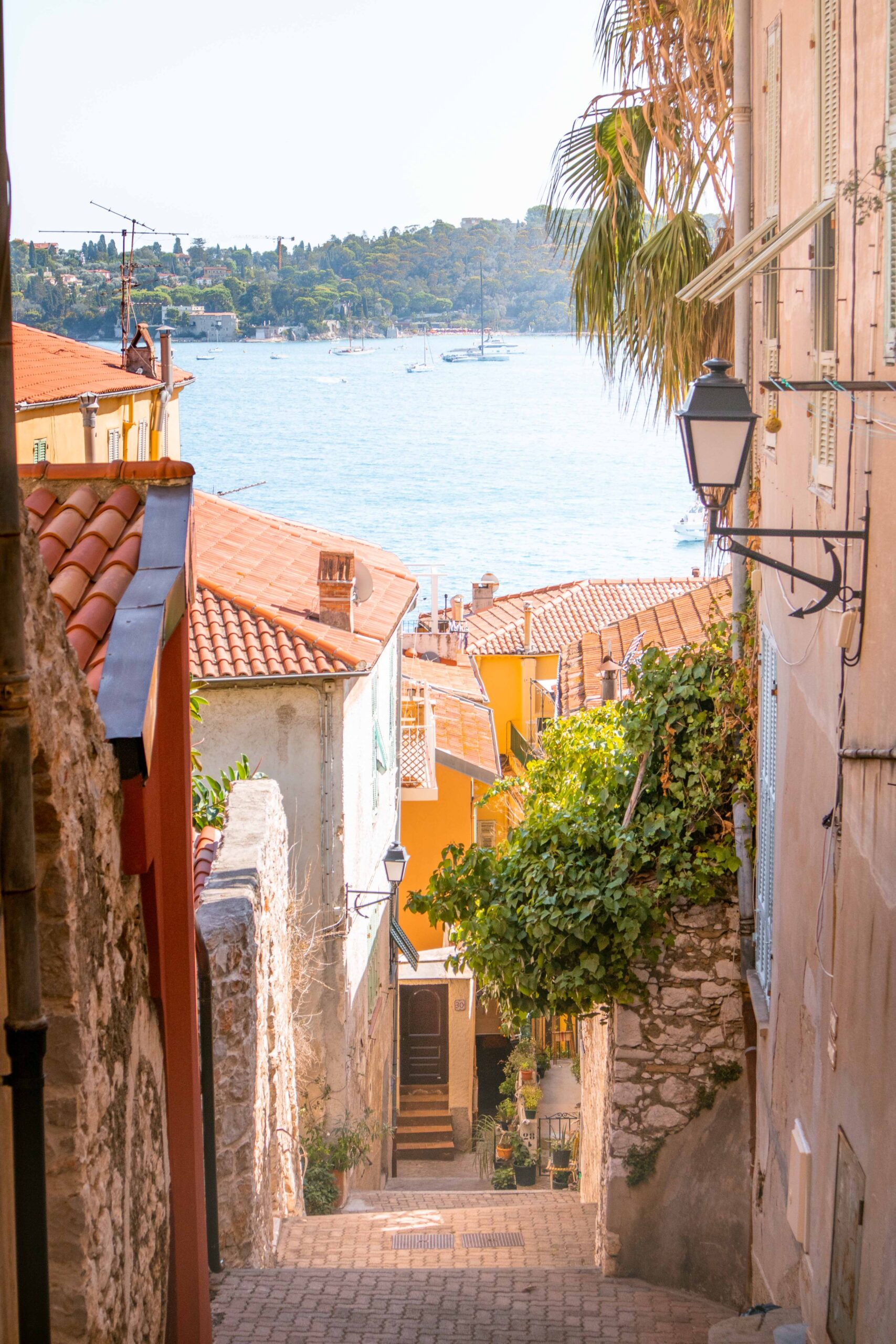 Colourful and empty street with a view over the Mediterranean sea and the Saint-Jean-Cap Ferrat peninsula in the Old Town of Villefranche-sur-Mer, France